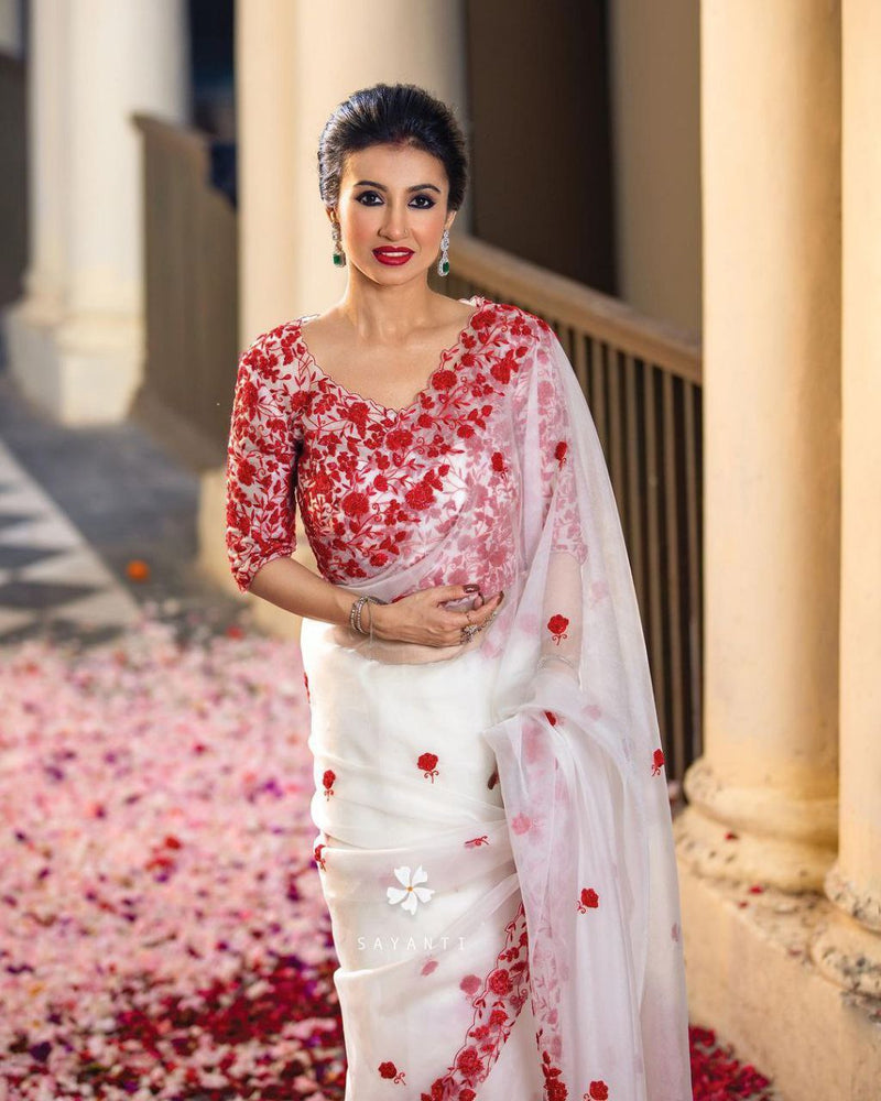 The ethereal looks resplendent in our white tissue organza saree. The drape showcases a scallop border with embroidery details Matched with a designer blouse Designer saree